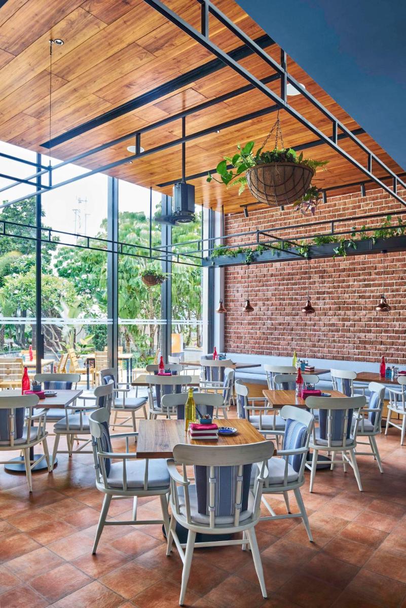 a restaurant with tables and chairs and a brick wall at Hyatt Centric MG Road Bangalore in Bengaluru a restaurant with tables and chairs and a brick wall at Hyatt Centric MG Road Bangalore in Bengaluru