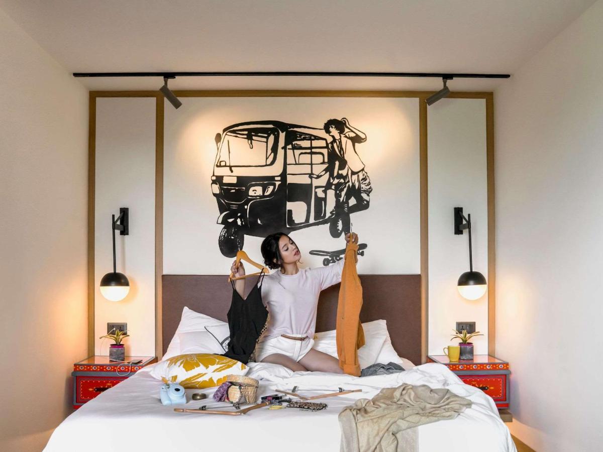 a woman is sitting on a bed with a picture on the wall at Hyatt Centric MG Road Bangalore in Bengaluru a woman is sitting on a bed with a picture on the wall at Hyatt Centric MG Road Bangalore in Bengaluru