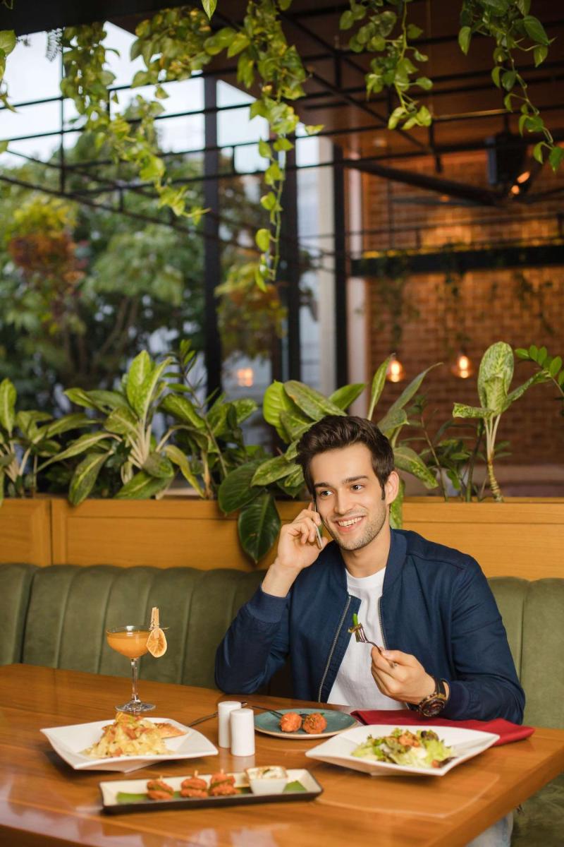 a man sitting at a table talking on a cell phone at Hyatt Centric MG Road Bangalore in Bengaluru a man sitting at a table talking on a cell phone at Hyatt Centric MG Road Bangalore in Bengaluru