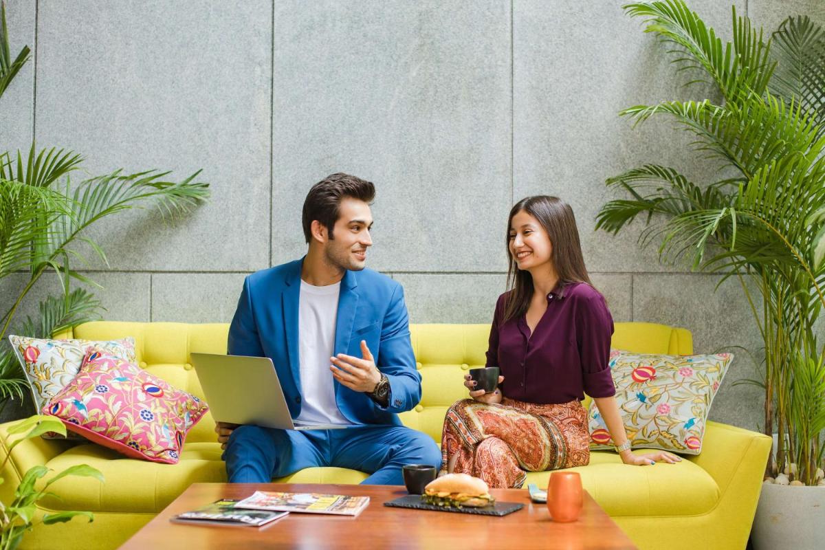 a man and a woman sitting on a couch with a laptop at Hyatt Centric MG Road Bangalore in Bengaluru a man and a woman sitting on a couch with a laptop at Hyatt Centric MG Road Bangalore in Bengaluru