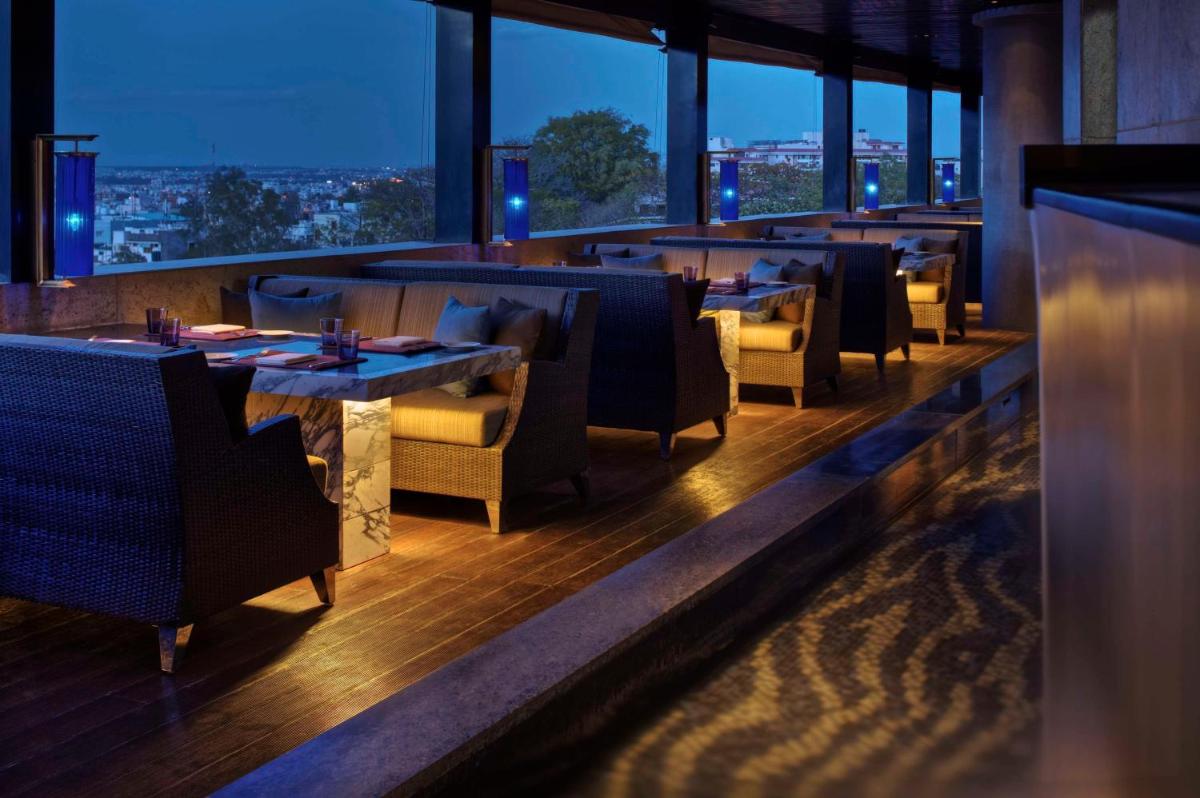 a restaurant with tables and chairs with a view at Park Hyatt Hotel and Residences, Hyderabad in Hyderabad