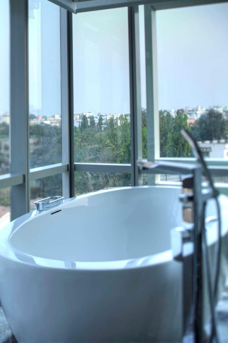 a white bath tub in a room with windows at Park Hyatt Hotel and Residences, Hyderabad in Hyderabad