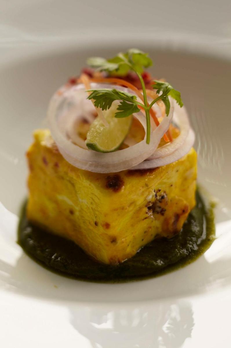 a piece of fish with onions on a white plate at Park Hyatt Hotel and Residences, Hyderabad in Hyderabad