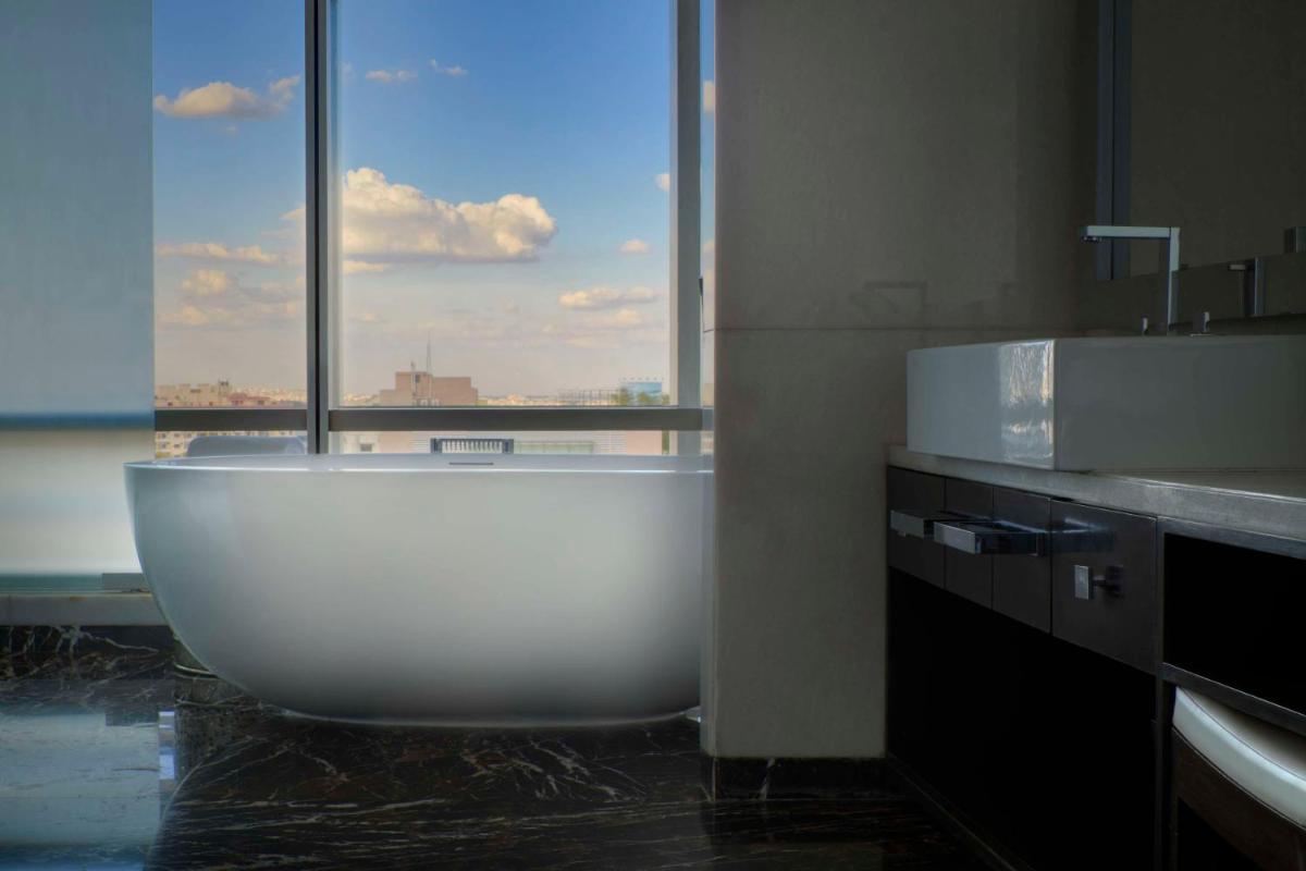 a large white bath tub in a bathroom with a window at Park Hyatt Hotel and Residences, Hyderabad in Hyderabad