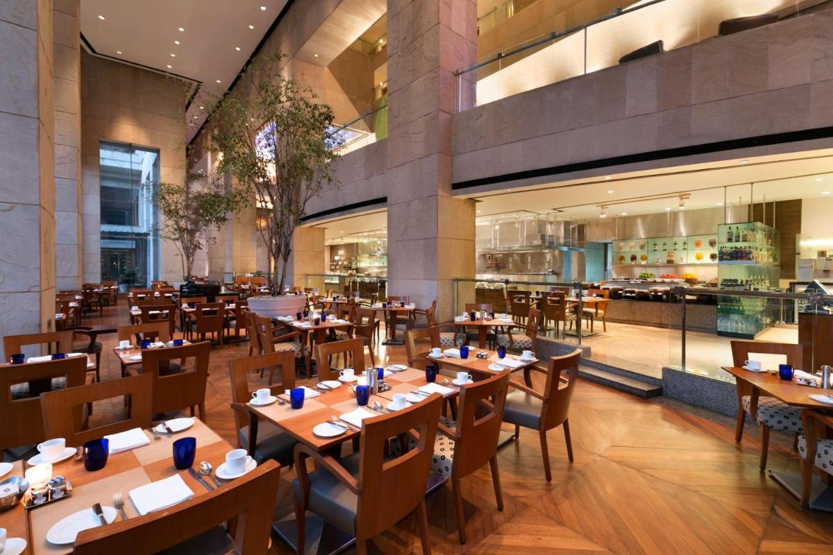 a restaurant with wooden tables and chairs in a building at Hyatt Regency Kolkata in Kolkata a restaurant with wooden tables and chairs in a building at Hyatt Regency Kolkata in Kolkata