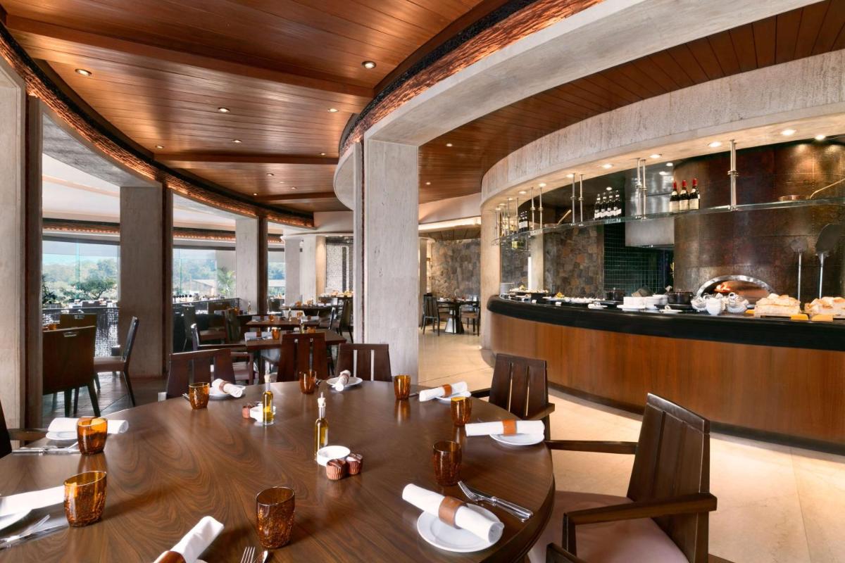 a restaurant with a long table and a bar at Hyatt Regency Kolkata in Kolkata a restaurant with a long table and a bar at Hyatt Regency Kolkata in Kolkata