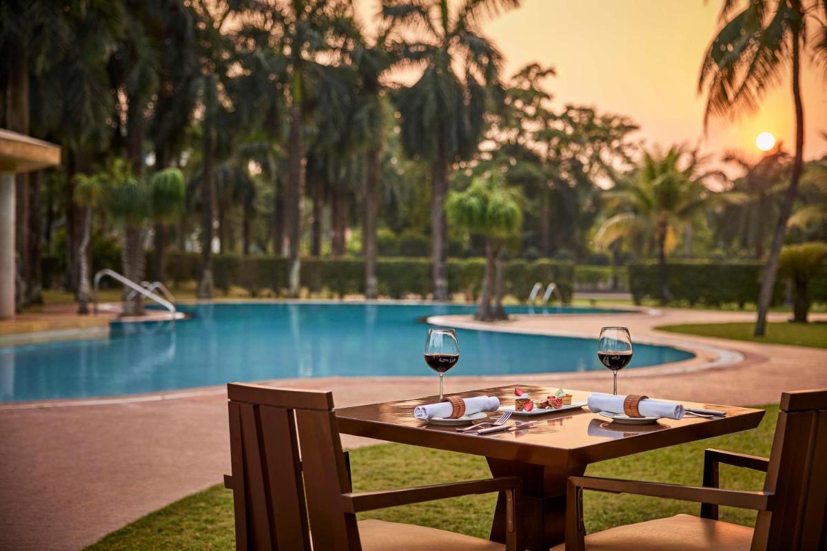a table with two glasses of wine next to a pool at Hyatt Regency Kolkata in Kolkata a table with two glasses of wine next to a pool at Hyatt Regency Kolkata in Kolkata