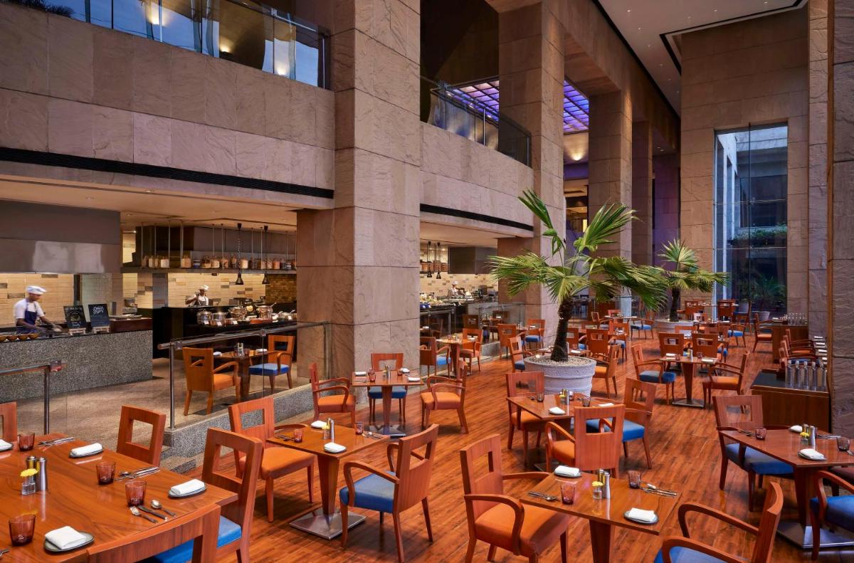 a restaurant with wooden tables and chairs in a building at Hyatt Regency Kolkata in Kolkata a restaurant with wooden tables and chairs in a building at Hyatt Regency Kolkata in Kolkata
