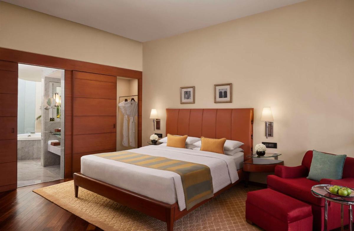 a bedroom with a large bed and a red chair at Hyatt Regency Kolkata in Kolkata a bedroom with a large bed and a red chair at Hyatt Regency Kolkata in Kolkata