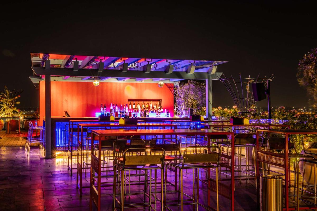 a bar with tables and chairs at night at Hyatt Place Hyderabad Banjara Hills in Hyderabad