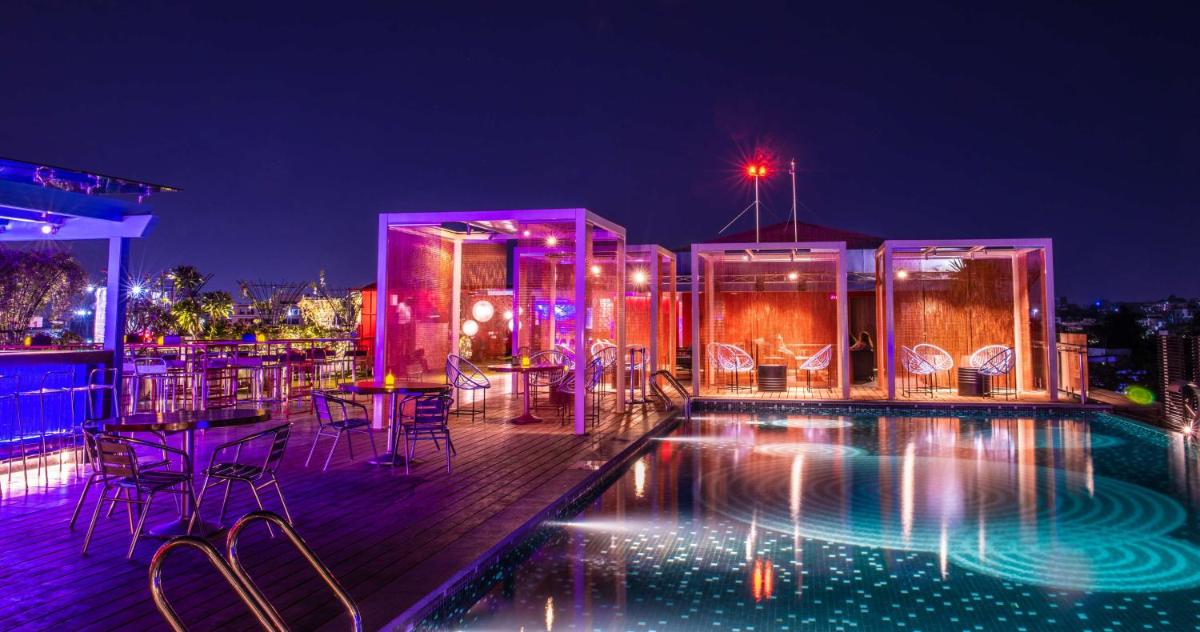 a rooftop patio with a swimming pool at night at Hyatt Place Hyderabad Banjara Hills in Hyderabad