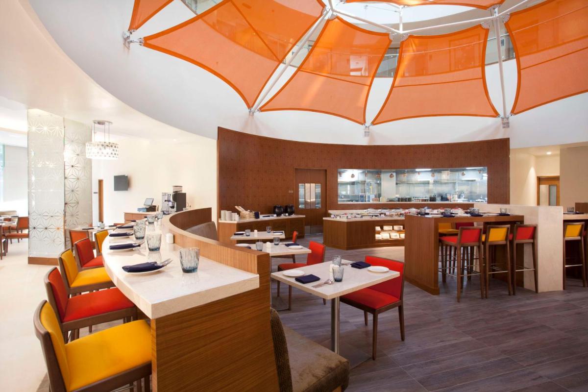 a restaurant with orange ceilings and tables and chairs at Hyatt Place Hyderabad Banjara Hills in Hyderabad