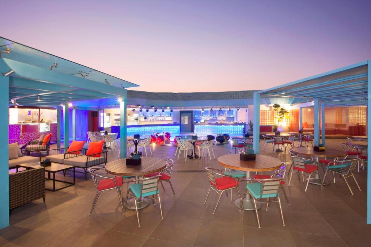 a restaurant with tables and chairs and a pool at Hyatt Place Hyderabad Banjara Hills in Hyderabad