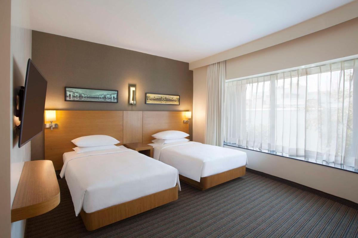 a hotel room with two beds and a window at Hyatt Place Hyderabad Banjara Hills in Hyderabad