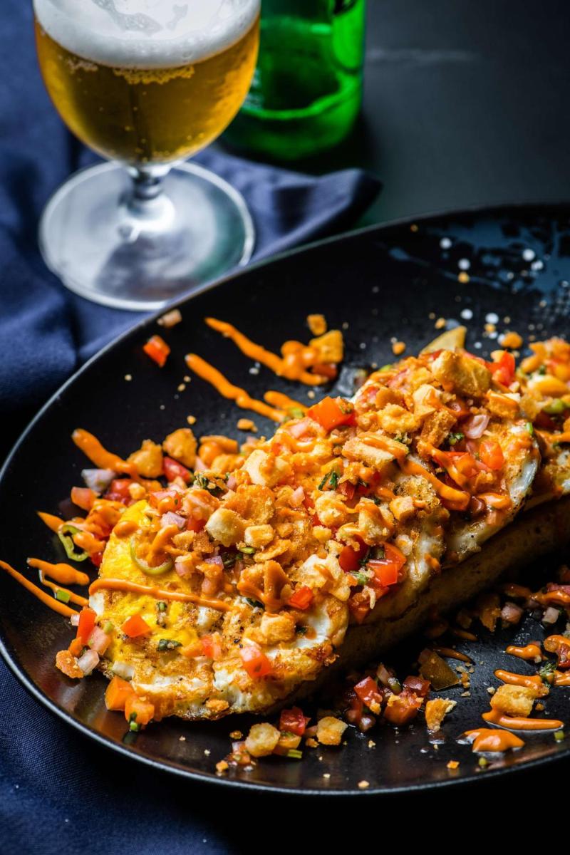 a plate of food on a table with a glass of beer at Hyatt Place Hyderabad Banjara Hills in Hyderabad