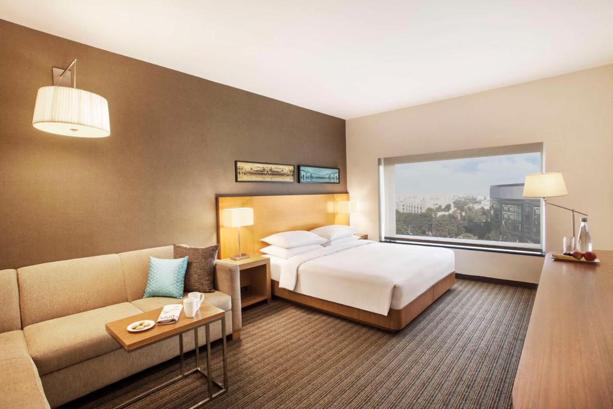 a hotel room with a bed and a couch at Hyatt Place Hyderabad Banjara Hills in Hyderabad