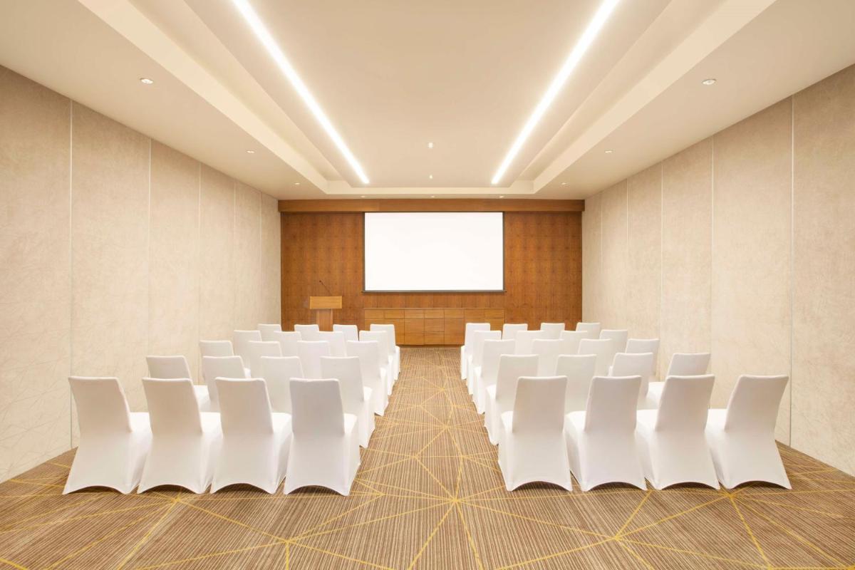 an empty conference room with white chairs and a screen at Hyatt Place Hyderabad Banjara Hills in Hyderabad