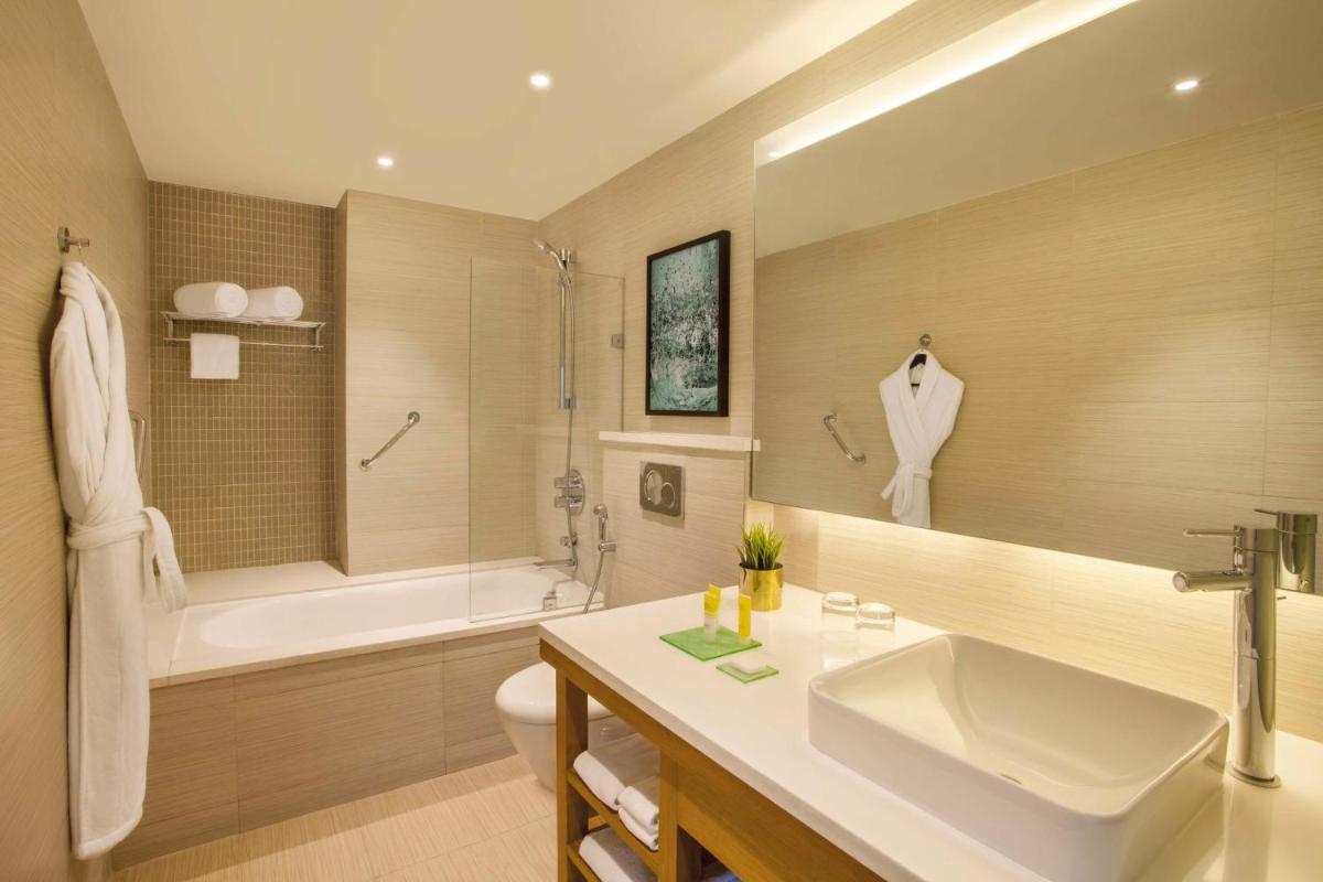 a bathroom with a sink and a tub and a toilet at Hyatt Place Hyderabad Banjara Hills in Hyderabad