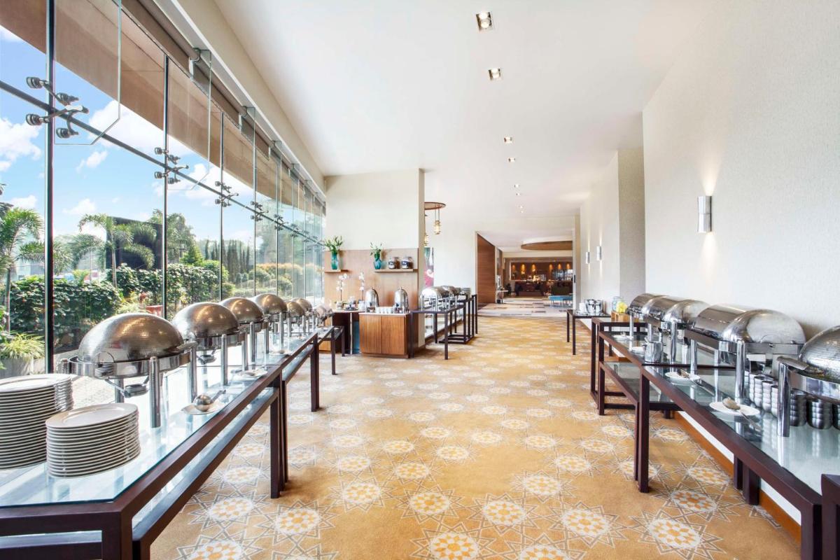 a restaurant with tables and chairs and a large window at Hyatt Place Hyderabad Banjara Hills in Hyderabad
