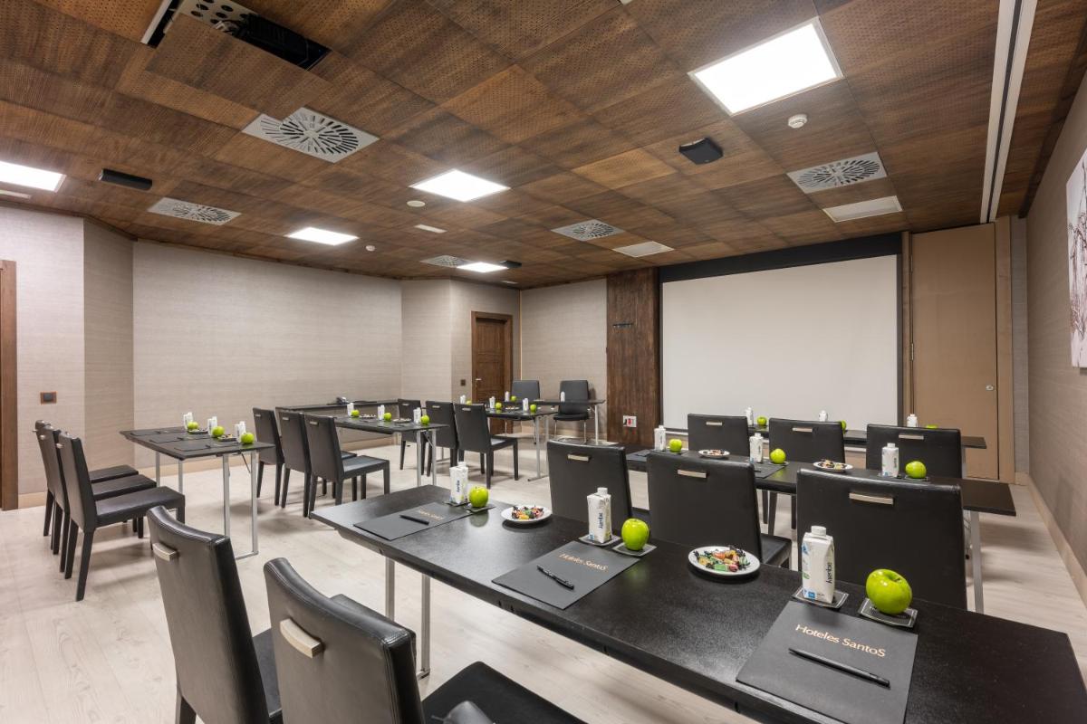 Una sala de conferencias con mesas, sillas y una pizarra. en Hotel Val de Neu G.L., en Baqueira Beret