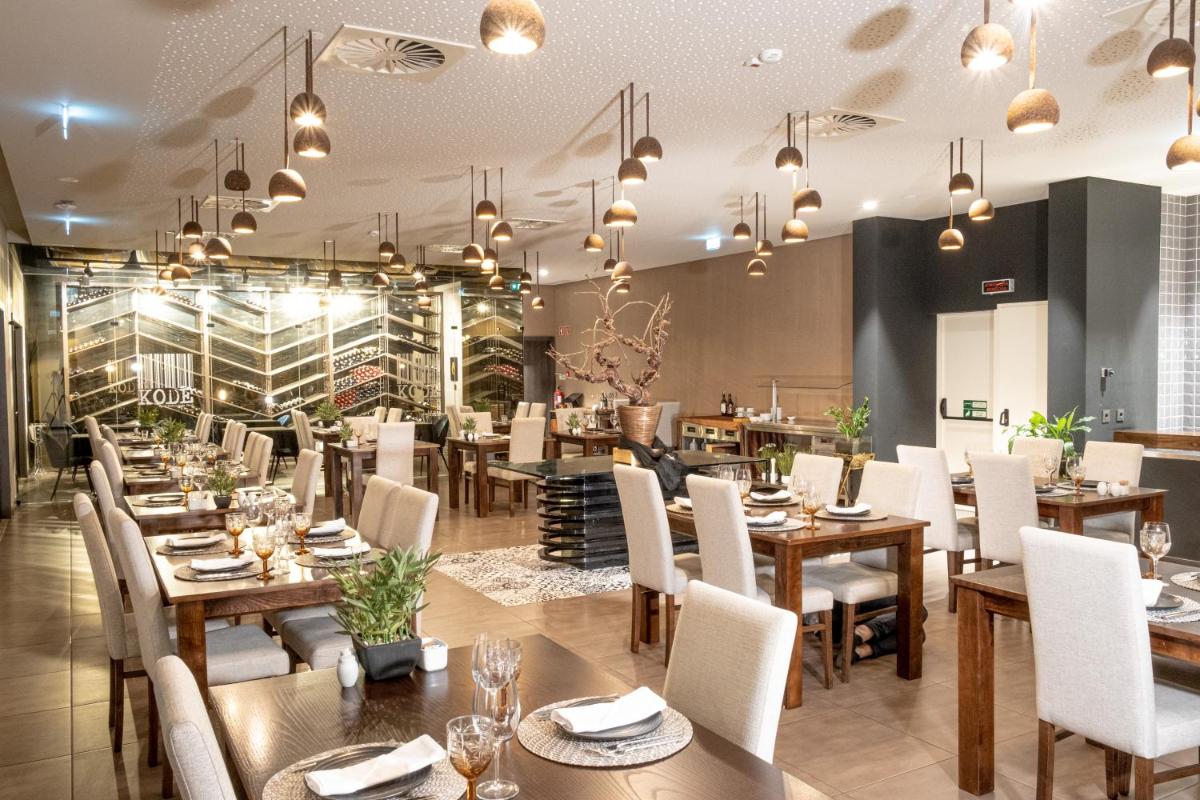 um restaurante com mesas de madeira e cadeiras brancas em MW Douro Wine & Spa em Santa Marta de Penaguião