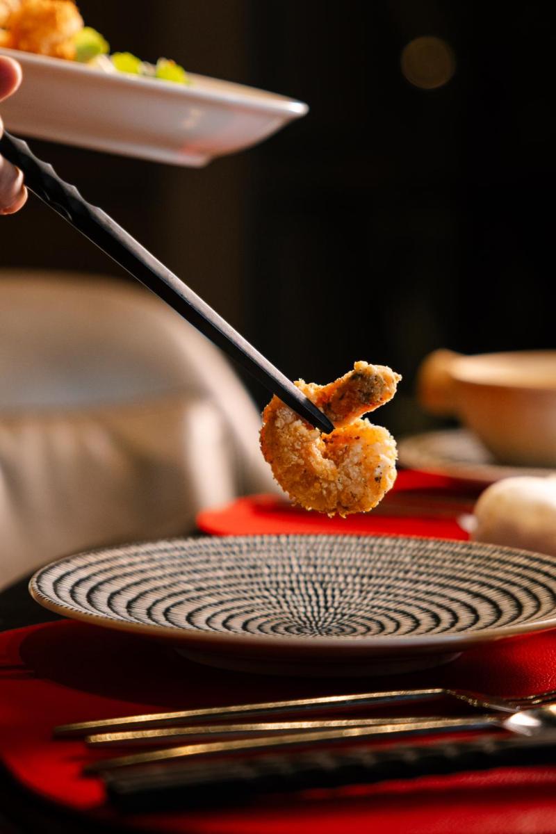 a person eating food with a utensil on a table at JW Marriott Hotel Kolkata in Kolkata
