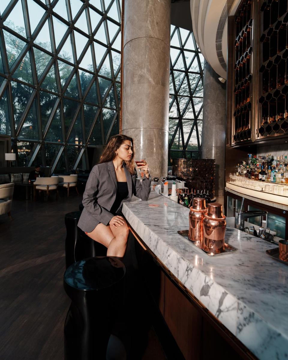 a woman sitting at a bar in a building at JW Marriott Hotel Kolkata in Kolkata