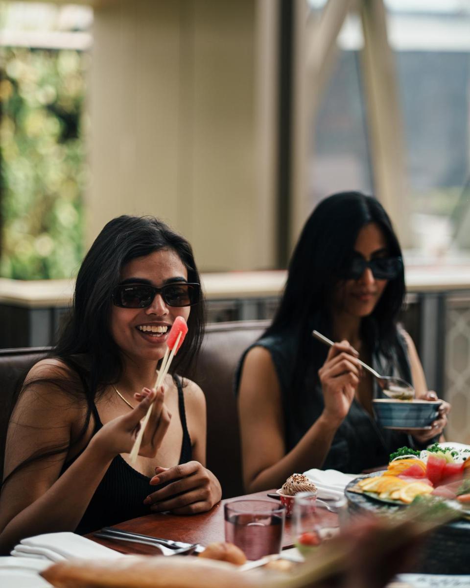two women sitting at a table eating food with chopsticks at JW Marriott Hotel Kolkata in Kolkata