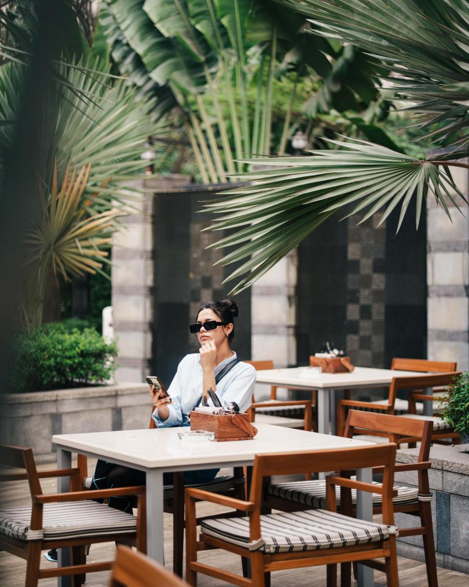 a woman sitting at a table looking at her cell phone at JW Marriott Hotel Kolkata in Kolkata