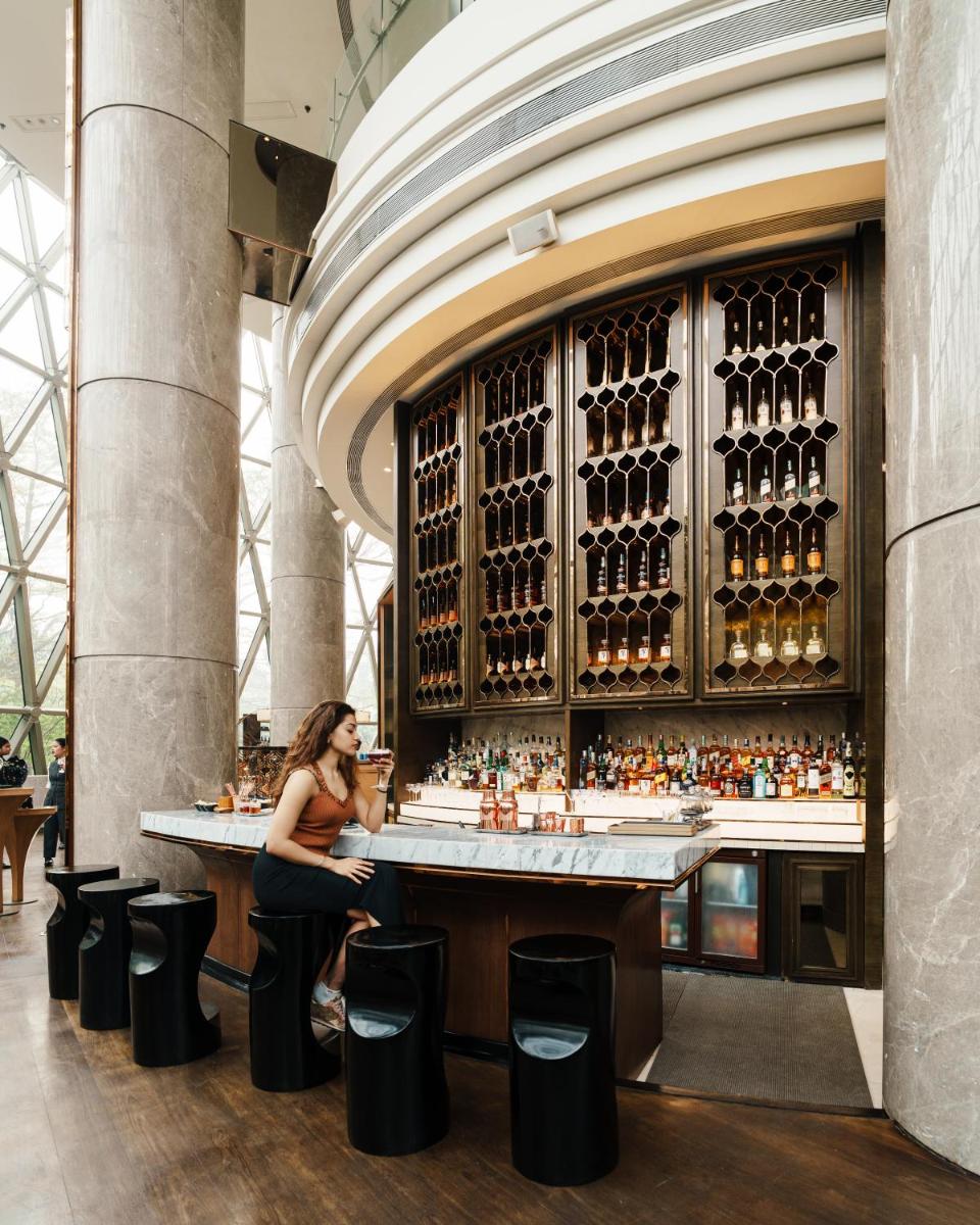 a woman sitting at a bar in a building at JW Marriott Hotel Kolkata in Kolkata