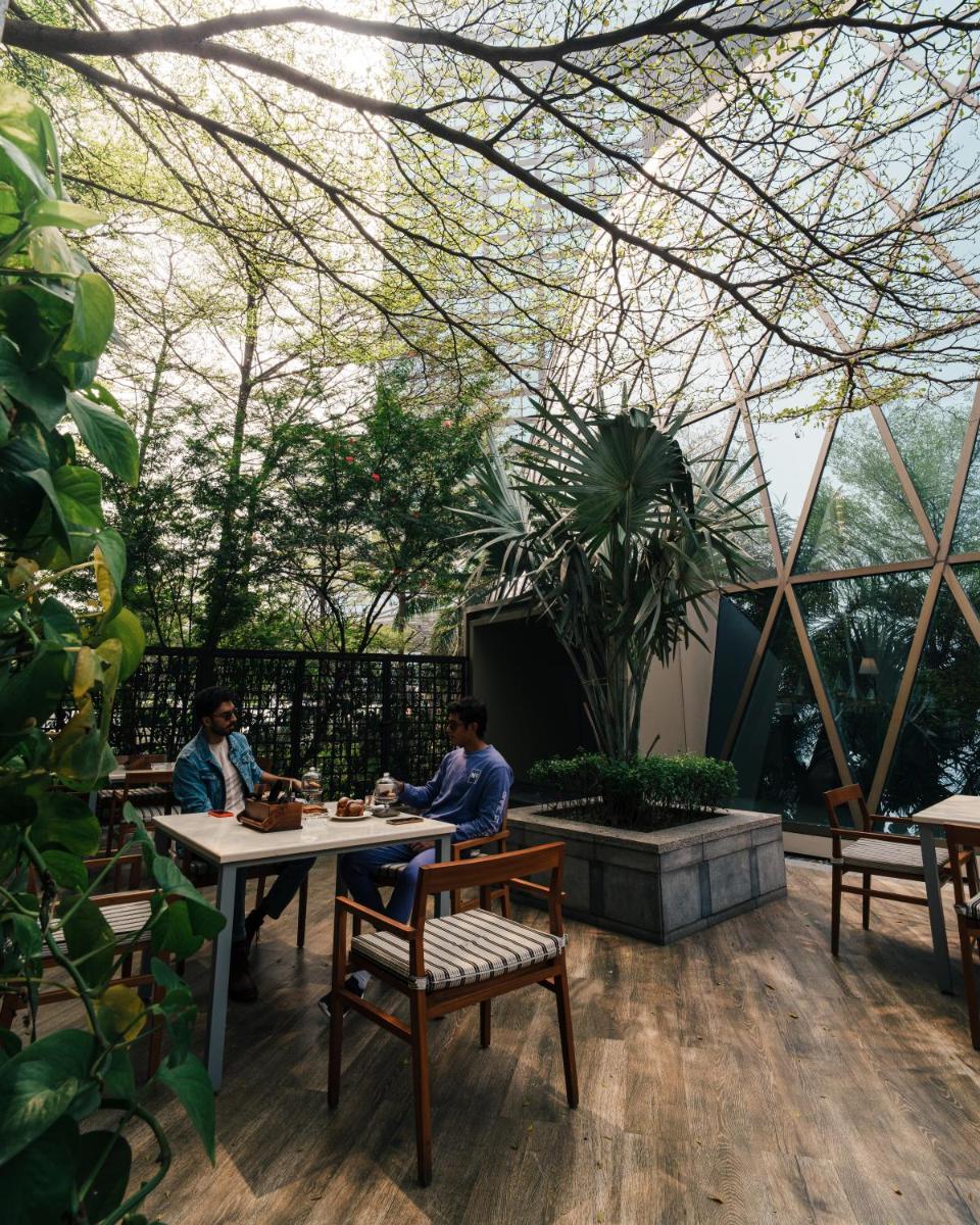 two people sitting at a table in a garden at JW Marriott Hotel Kolkata in Kolkata