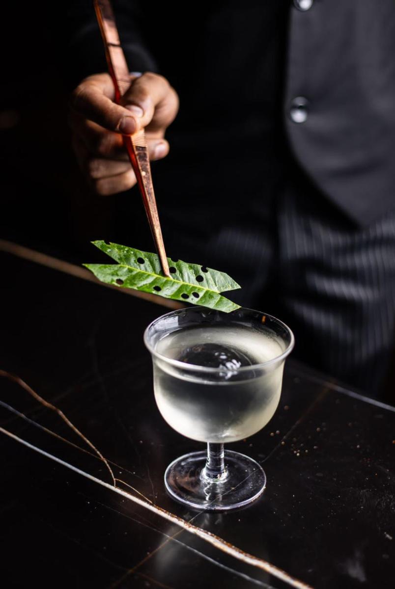 a person holding a knife and a plate with a drink at JW Marriott Hotel Kolkata in Kolkata