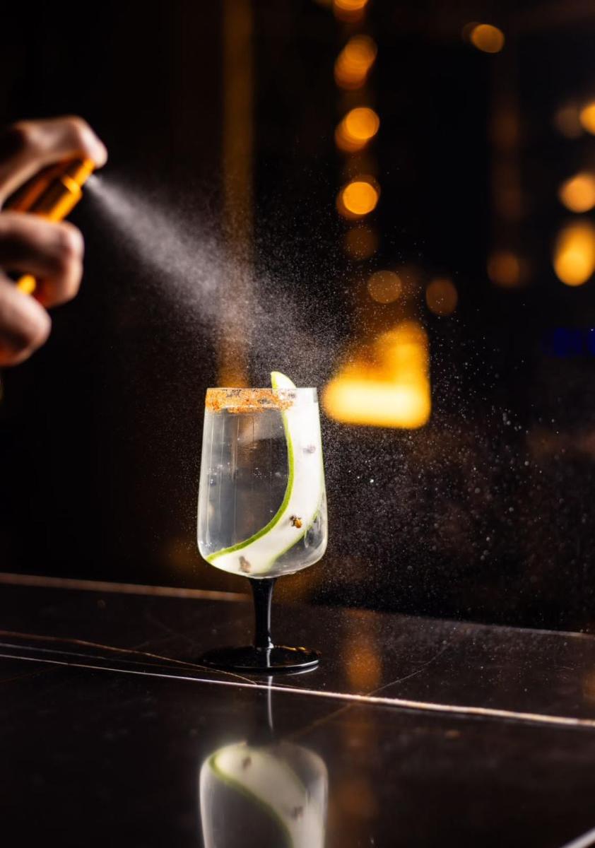 a person sprinkling a drink in a wine glass at JW Marriott Hotel Kolkata in Kolkata