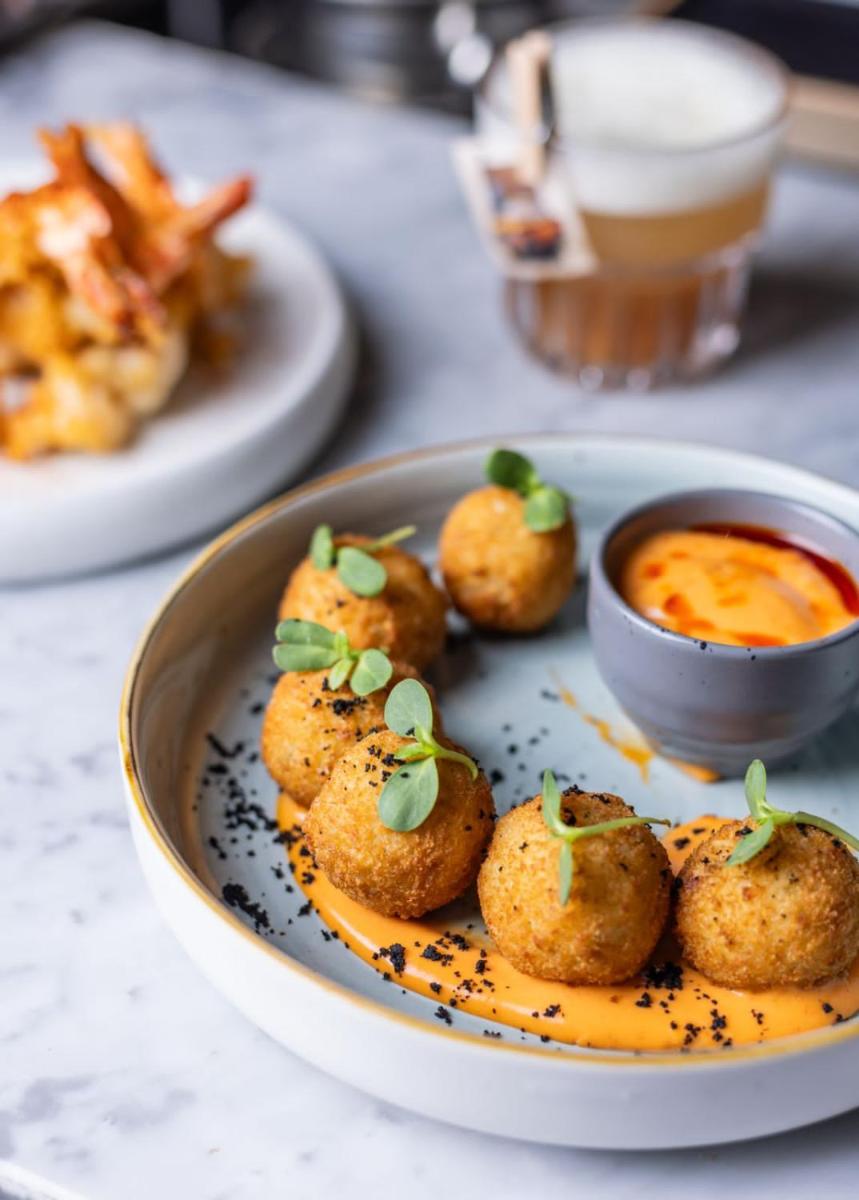 a plate of food with potatoes and dipping sauce at JW Marriott Hotel Kolkata in Kolkata