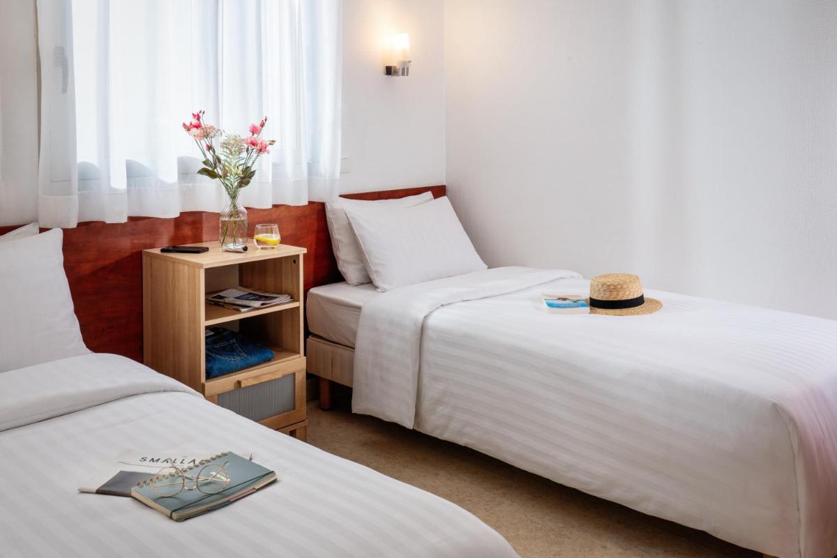 une chambre d'hôtel avec deux lits et un vase de fleurs dans l'établissement Résidences Valdys Thalasso & Spa de Rockroum, à Roscoff