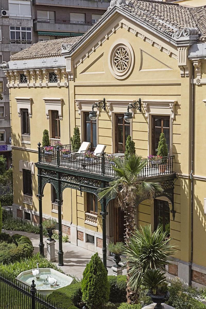 Casa amarilla con balcón y palmera en Hospes Palacio de los Patos, a Member of Design Hotels, en Granada