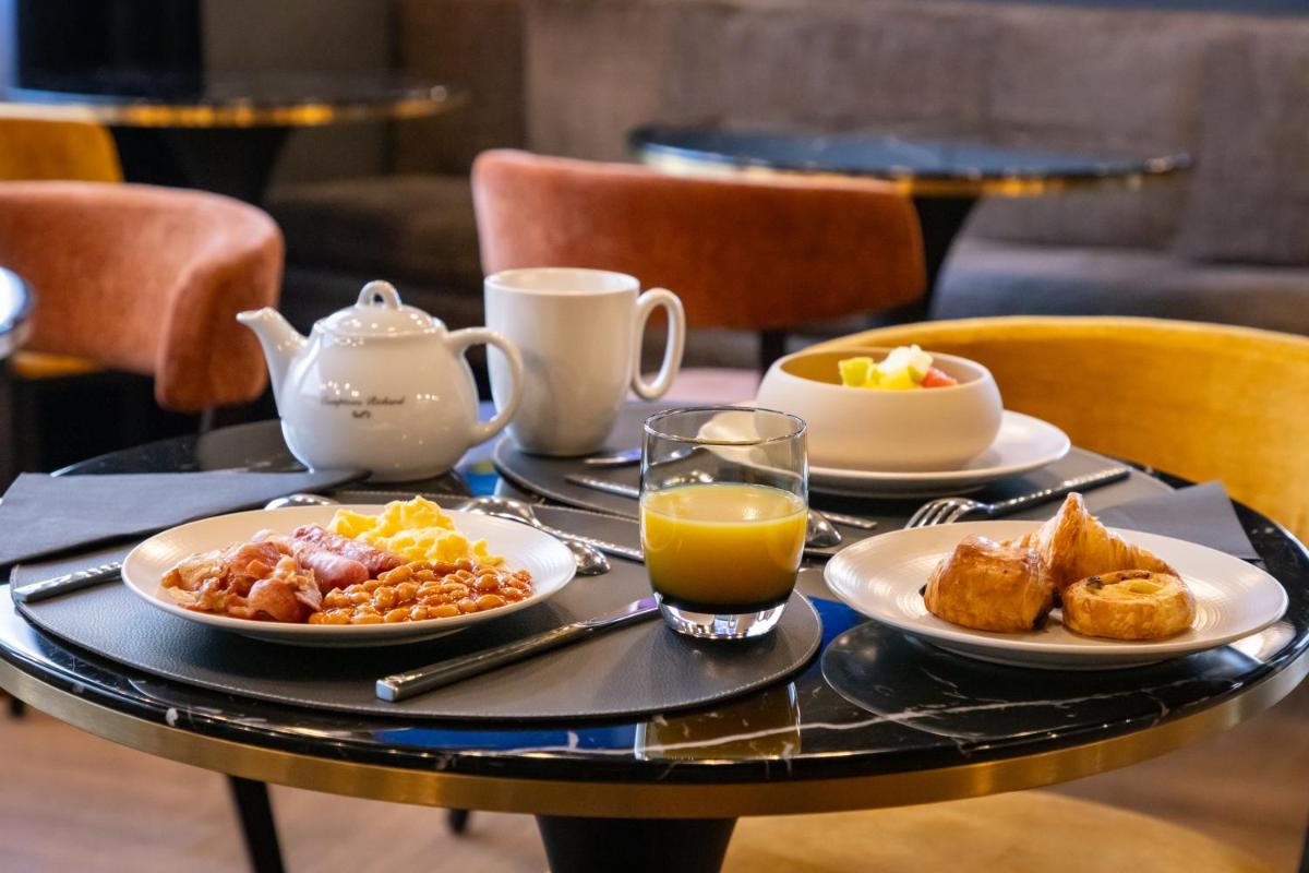 - une table avec des assiettes de produits pour le petit-déjeuner et du jus d'orange dans l'établissement Hôtel & Spa Le Maury, Vannes, The Originals Boutique, à Vannes 37 autres photos