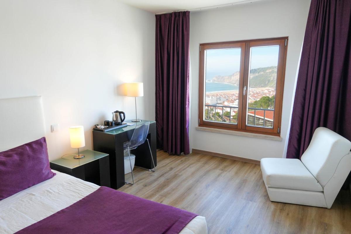 um quarto de hotel com uma cama e uma janela em Miramar Hotel Spa & Apartments na Nazaré
