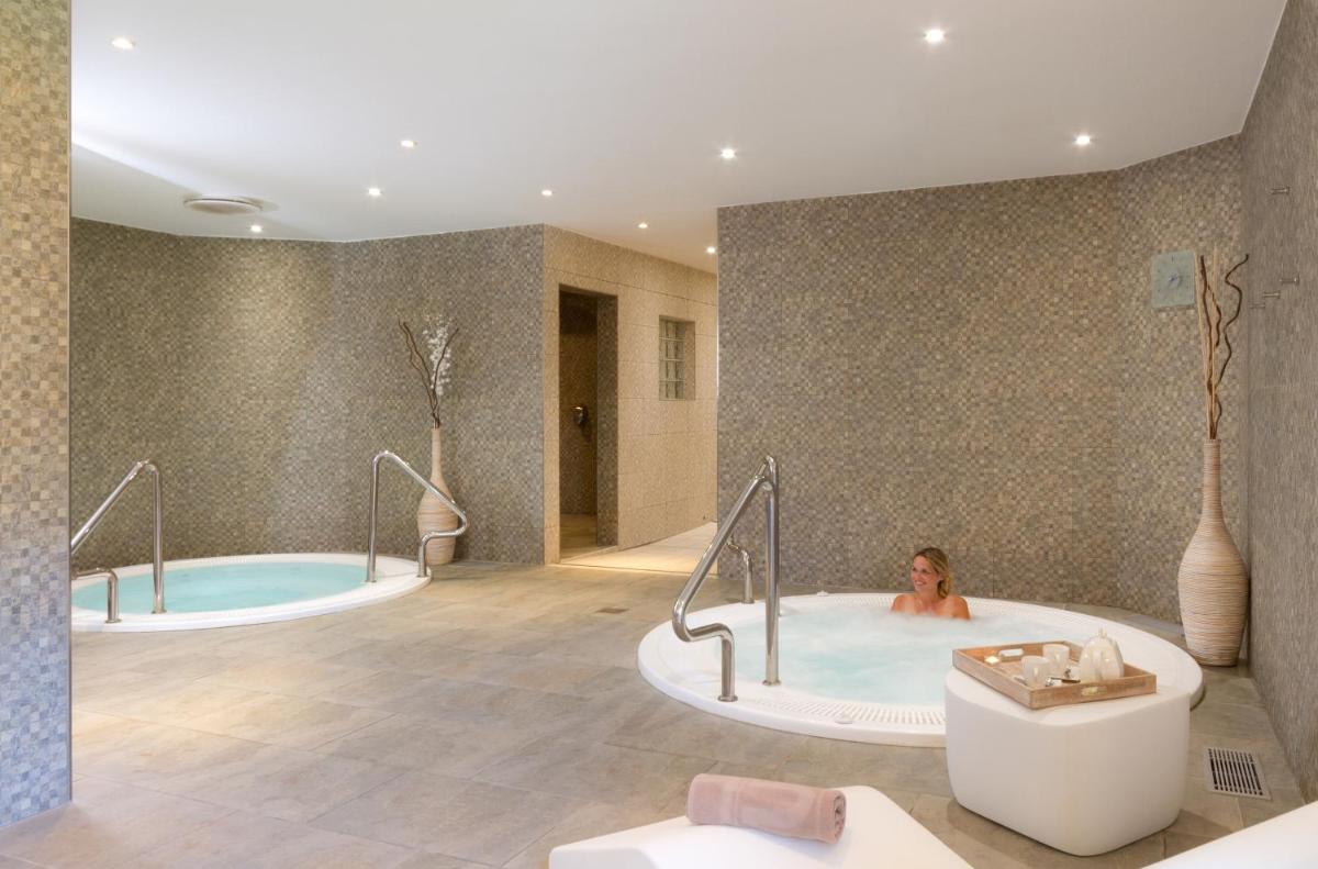 une femme dans une baignoire dans une salle de bains dans l'établissement Résidence Club mmv Le Hameau des Airelles ****, à Montgenèvre