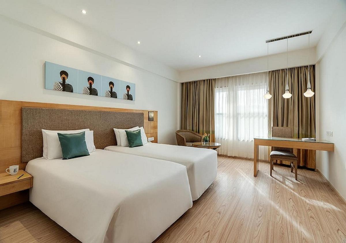 a hotel room with a large white bed and a desk at Greenpark Chennai in Chennai