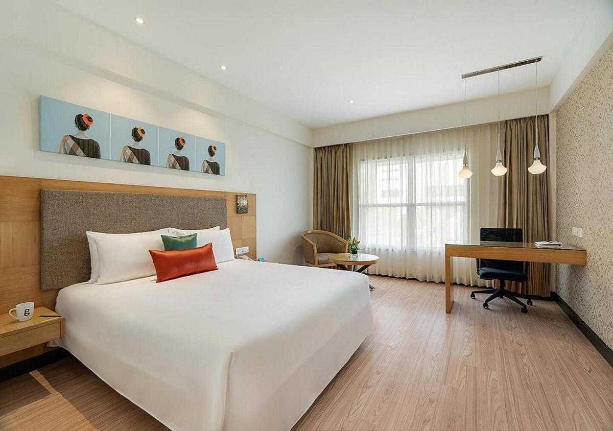 a hotel room with a large white bed and a desk at Greenpark Chennai in Chennai +8 photos
