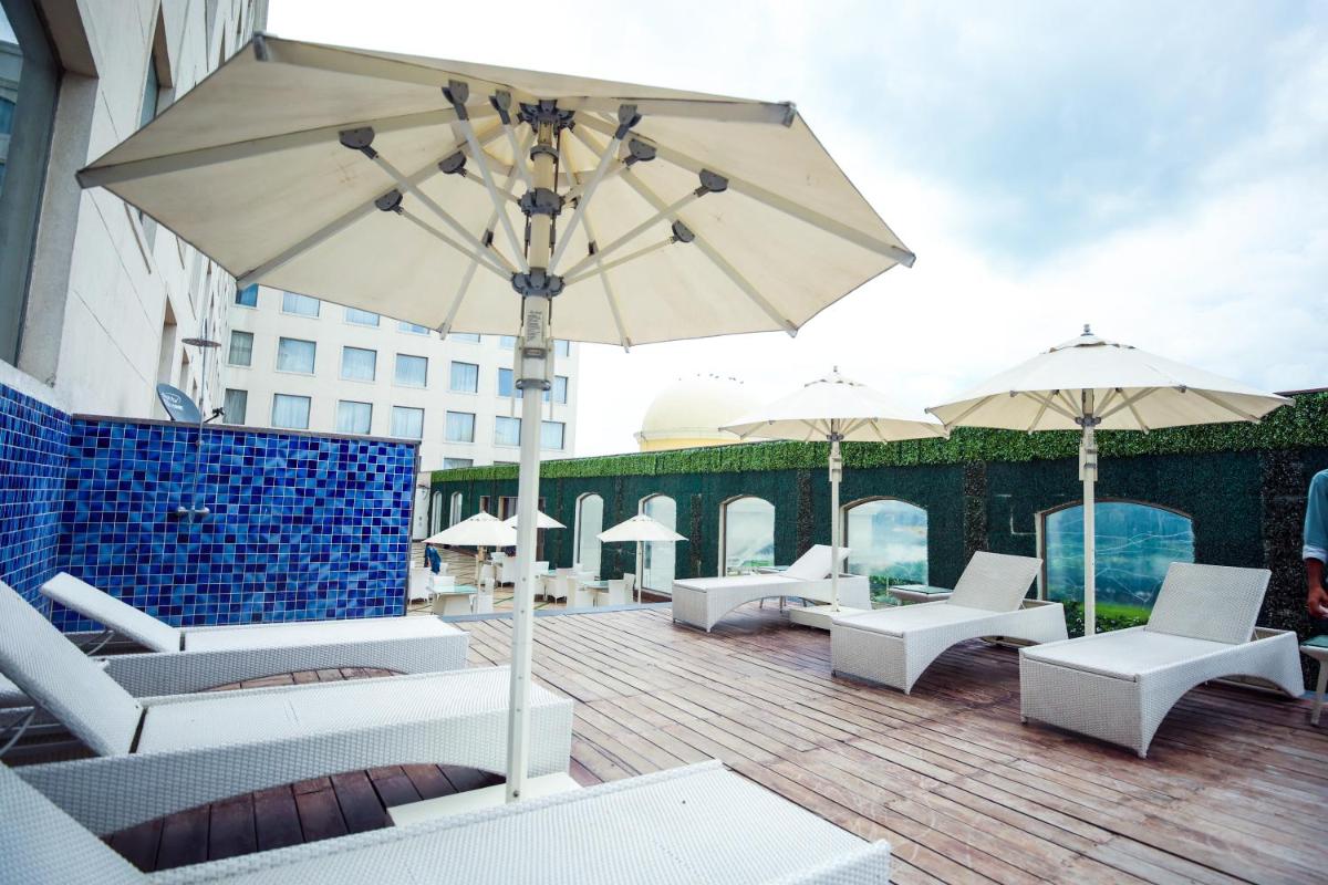 a patio with white chairs and an umbrella at Ramada by Wyndham Lucknow Hotel and Convention Center in Lucknow