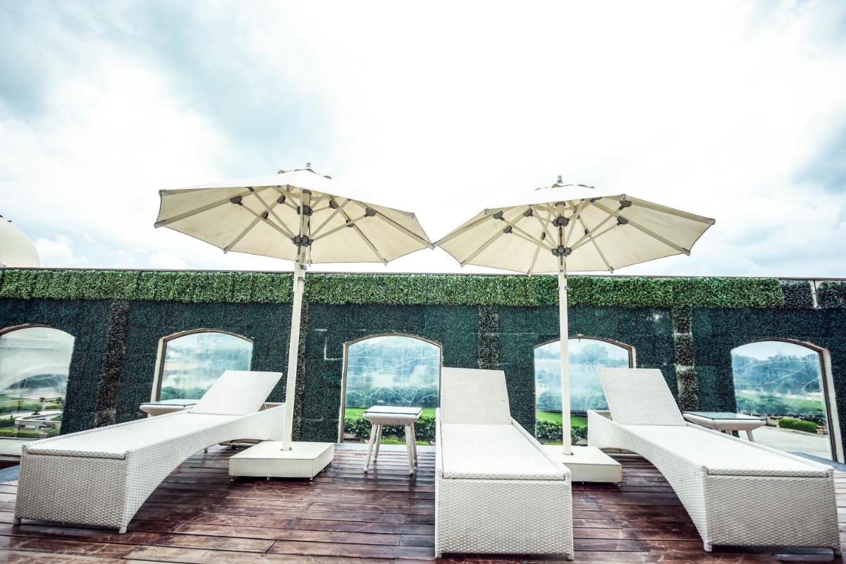 a patio with white chairs and tables and umbrellas at Ramada by Wyndham Lucknow Hotel and Convention Center in Lucknow