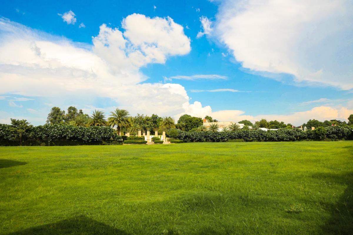 a large field of green grass with a blue sky at Ramada by Wyndham Lucknow Hotel and Convention Center in Lucknow