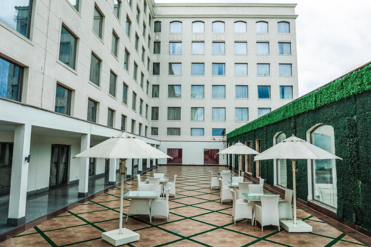 a row of white chairs and umbrellas on a courtyard at Ramada by Wyndham Lucknow Hotel and Convention Center in Lucknow