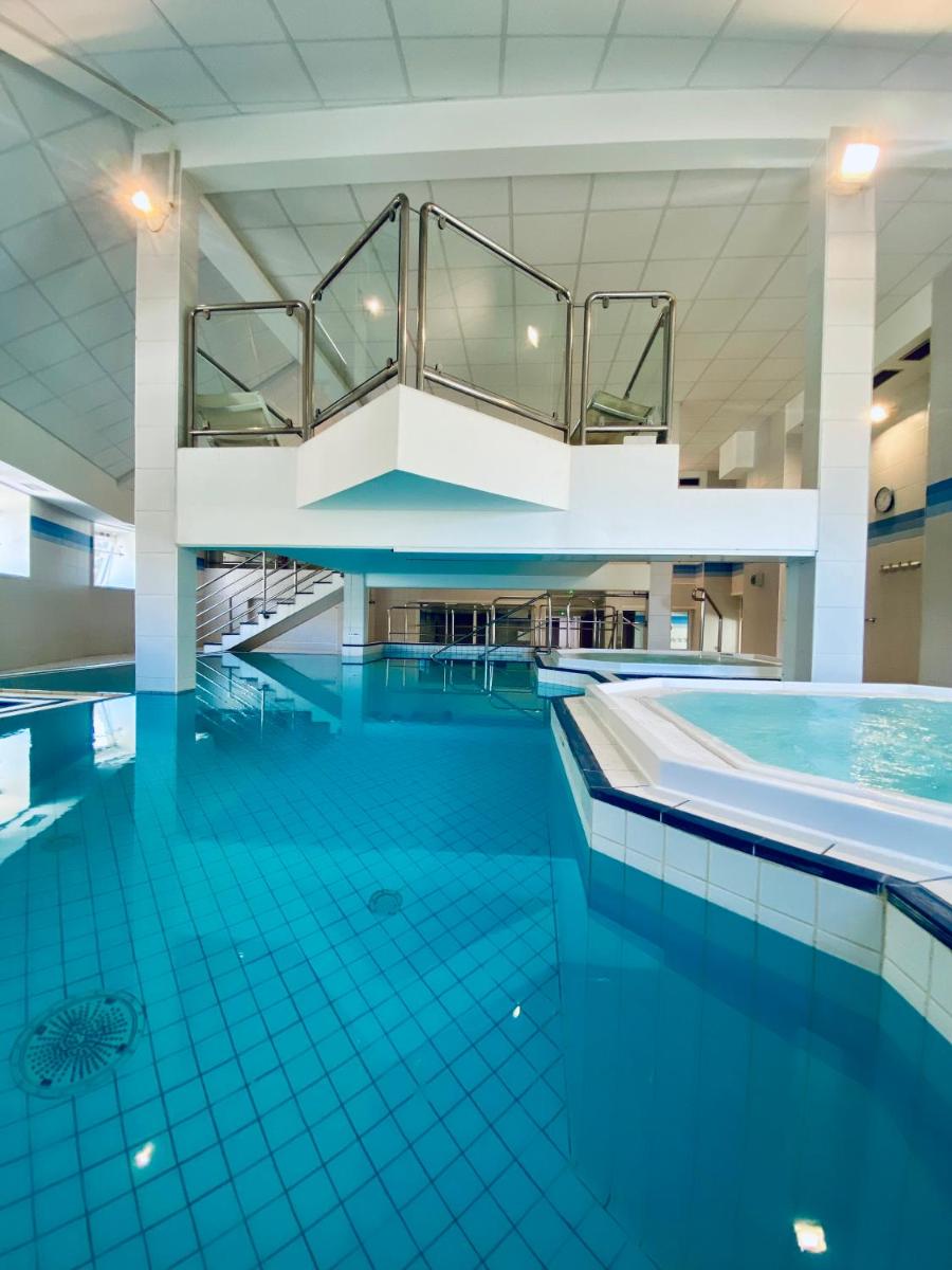 une grande piscine avec un sol en carrelage bleu dans l'établissement Résidence Le Grand Tétras- SPA THERMAL INCLUS, à Ax-les-Thermes