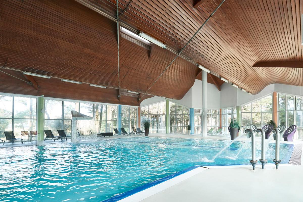 une grande piscine dans un immeuble avec une grande fenêtre dans l'établissement Hôtel Valdys Thalasso & Spa - les Pins, à Saint-Jean-de-Monts