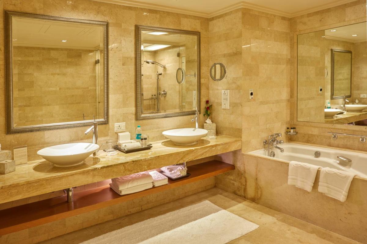 a bathroom with two sinks and a tub and mirrors at The Leela Mumbai in Mumbai a bathroom with two sinks and a tub and mirrors at The Leela Mumbai in Mumbai