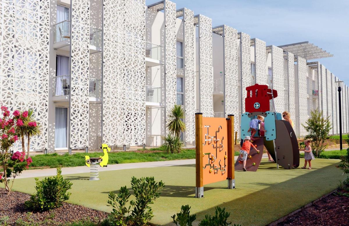 - une aire de jeux pour enfants en face d'un bâtiment dans l'établissement Appart'Hotel Odalys Nakâra, au Cap d'Agde