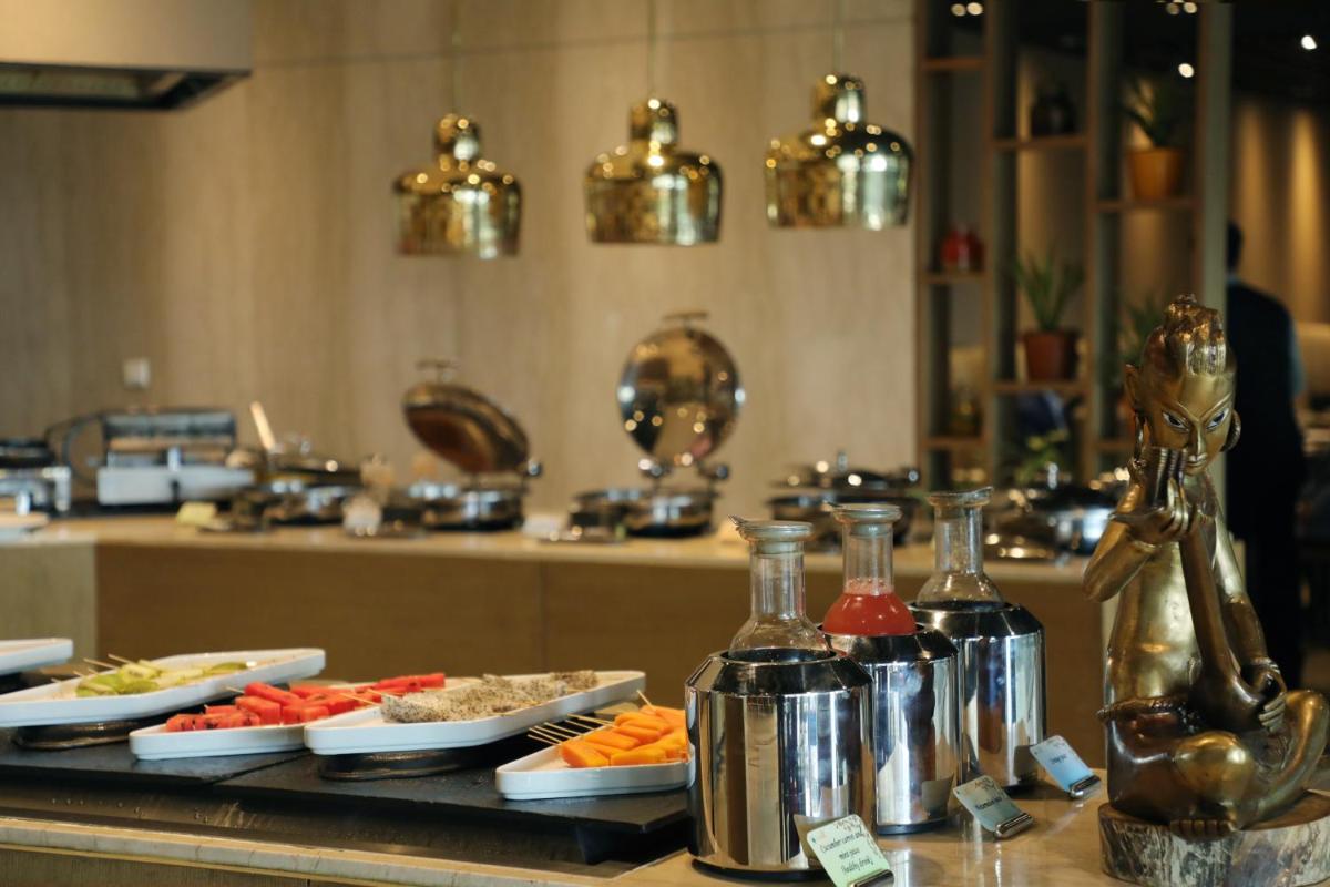 a buffet with plates of food and bottles of alcohol at The Leela Ambience Convention Hotel Delhi in New Delhi